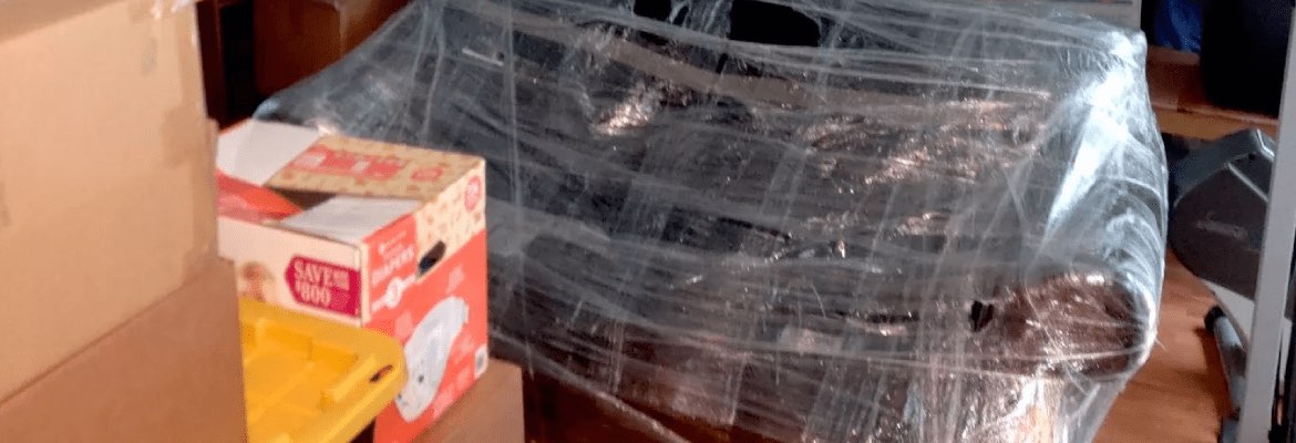 A sofa wrapped in clear plastic among packed boxes