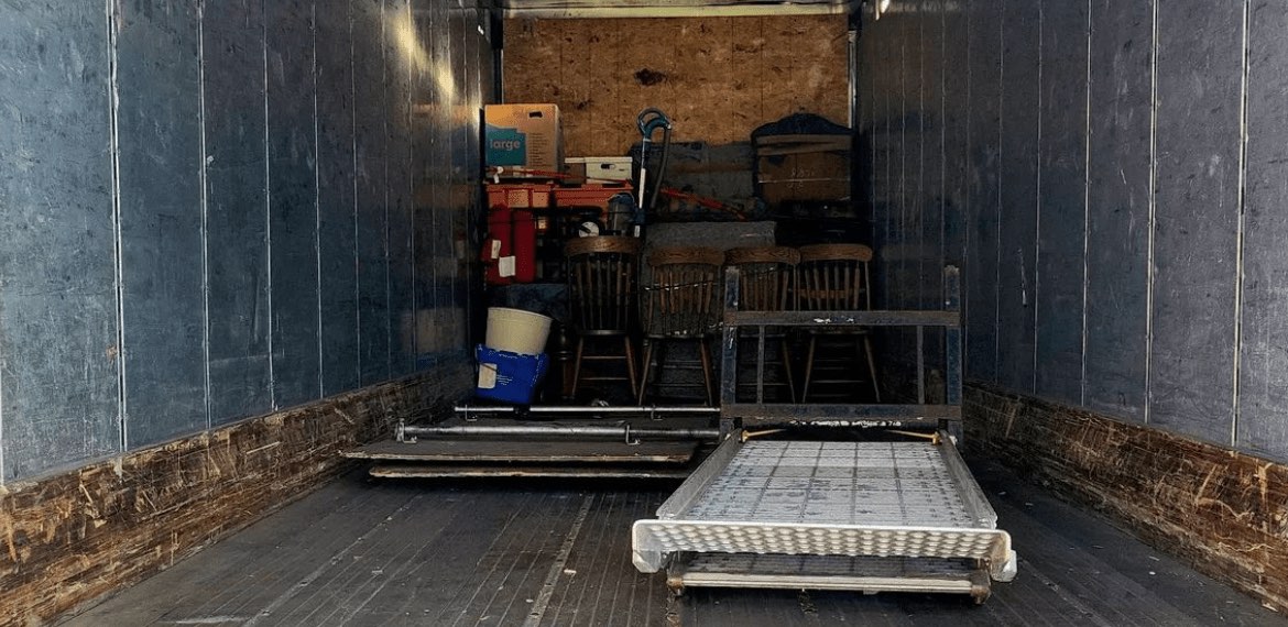 An open box truck with a bed frame and furniture ready to load